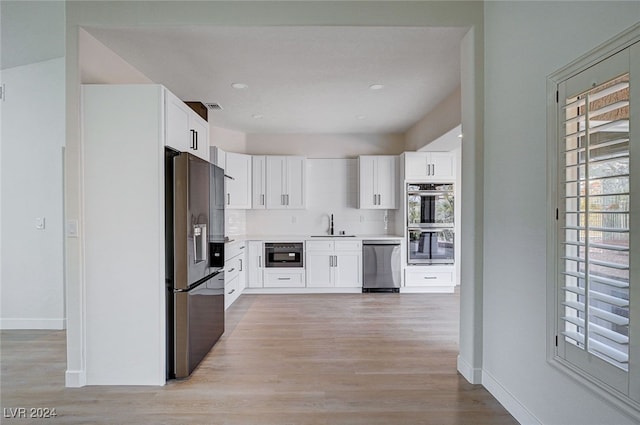 kitchen with sink, light hardwood / wood-style flooring, backsplash, white cabinets, and appliances with stainless steel finishes