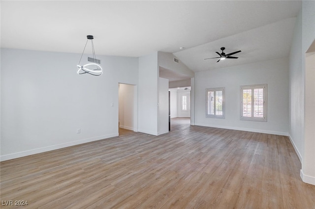 unfurnished room featuring ceiling fan with notable chandelier, light hardwood / wood-style floors, and lofted ceiling