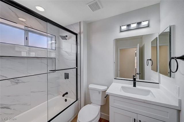 full bathroom featuring vanity, toilet, and shower / bath combination with glass door