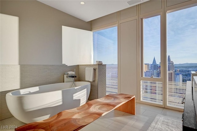 bathroom featuring tile patterned flooring, a bath, and tile walls