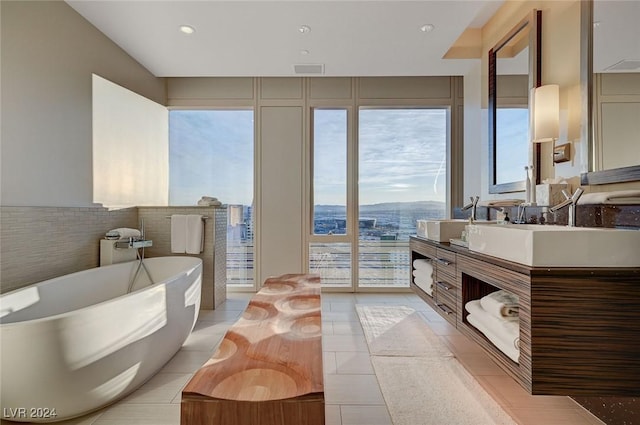 bathroom with tile patterned flooring, a bath, vanity, and tile walls