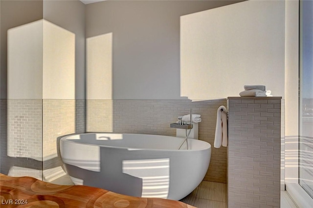 bathroom with tile patterned flooring, a tub to relax in, and tile walls