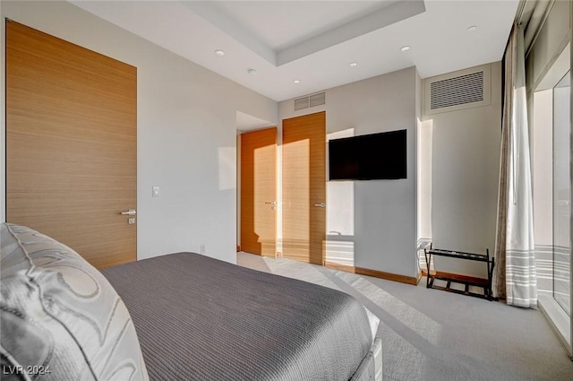 bedroom with a raised ceiling and light carpet