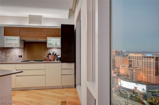 kitchen with backsplash, light hardwood / wood-style floors, stainless steel gas stovetop, and exhaust hood