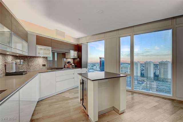 kitchen featuring stainless steel gas stovetop, a center island, light hardwood / wood-style flooring, decorative backsplash, and white cabinetry