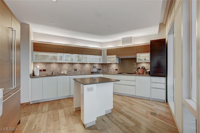 kitchen with white cabinets, a center island, light hardwood / wood-style flooring, and backsplash