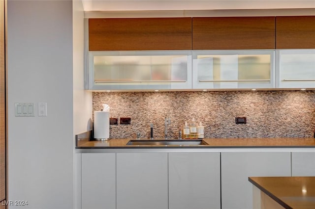 bar featuring backsplash, white cabinetry, and sink