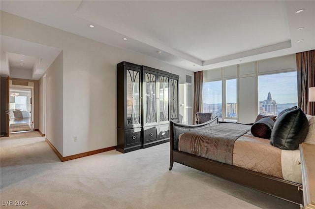 bedroom with light colored carpet and a tray ceiling