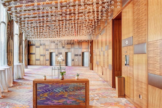 corridor with wooden walls and lofted ceiling