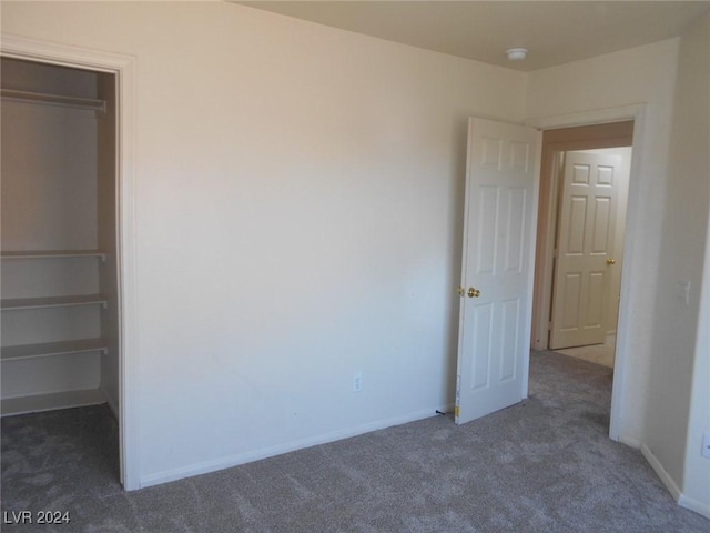 unfurnished bedroom featuring a closet and dark colored carpet