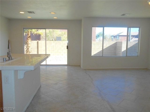 interior space with white cabinetry, sink, light tile patterned floors, and a healthy amount of sunlight