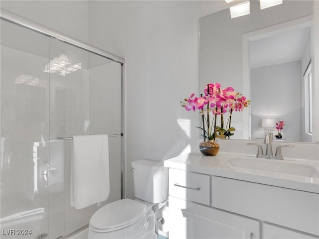 bathroom featuring toilet, vanity, and a shower with shower door