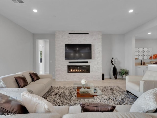 living room with a stone fireplace and light hardwood / wood-style floors