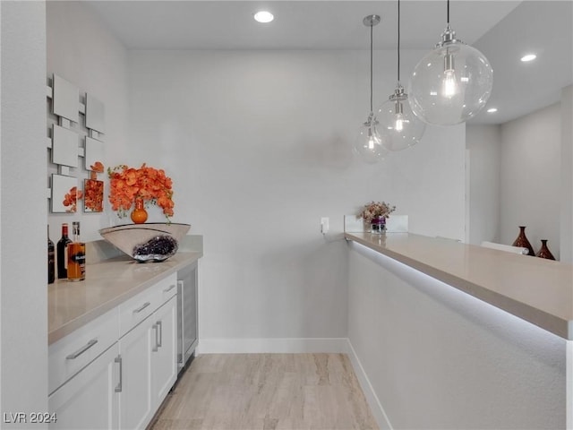 bar featuring pendant lighting, white cabinets, and light hardwood / wood-style flooring