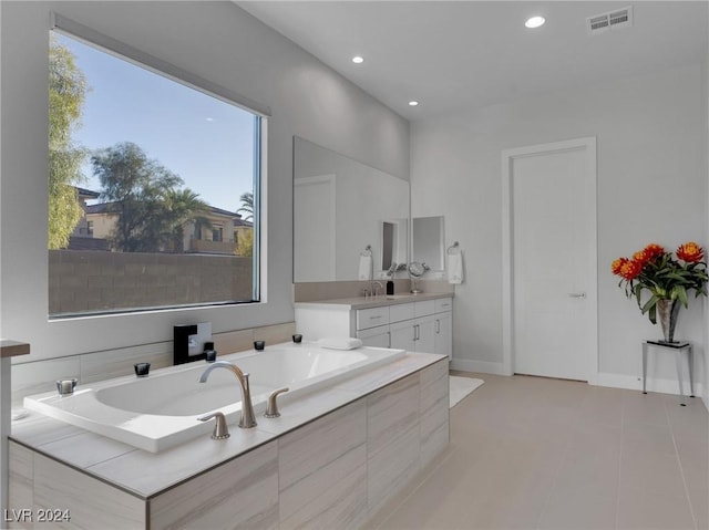 bathroom with tile patterned floors, tiled bath, and vanity