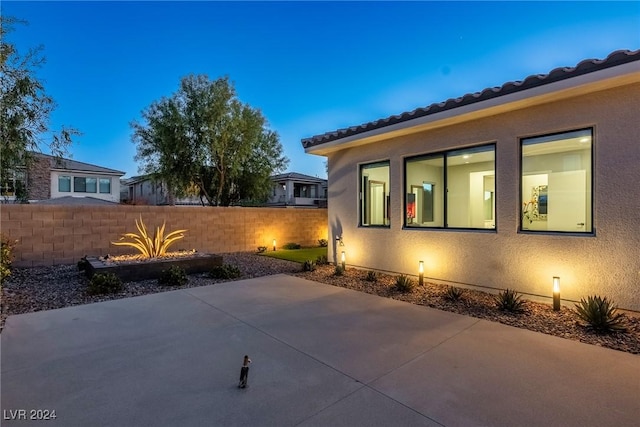 property exterior at dusk featuring a patio