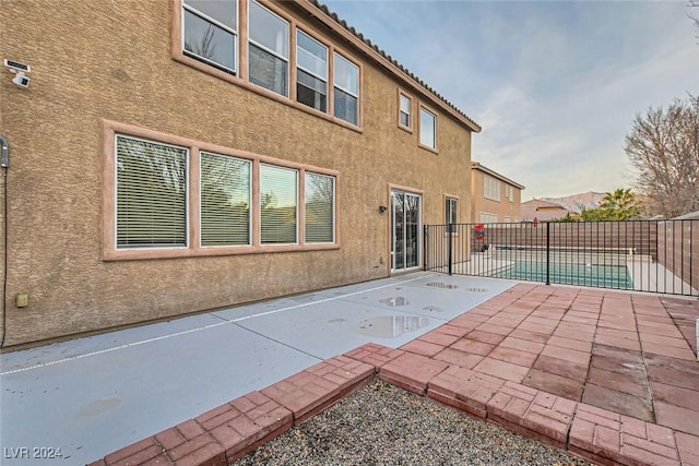 back of property featuring a fenced in pool and a patio