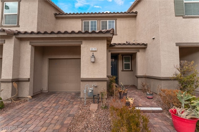 property entrance with a garage, decorative driveway, and stucco siding