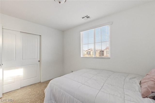 bedroom with light colored carpet and a closet