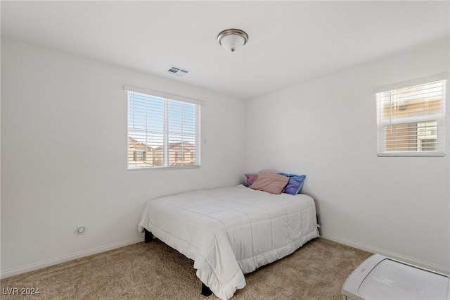 bedroom with light colored carpet and multiple windows