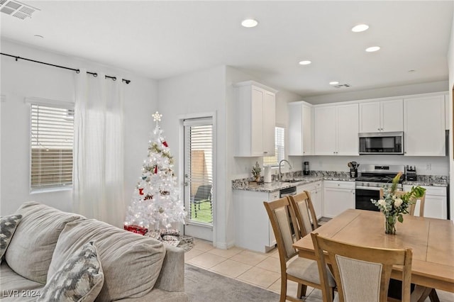 kitchen featuring white cabinetry, sink, light tile patterned floors, and appliances with stainless steel finishes