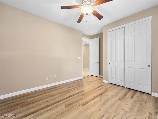 unfurnished bedroom featuring ceiling fan, a closet, and light wood-type flooring