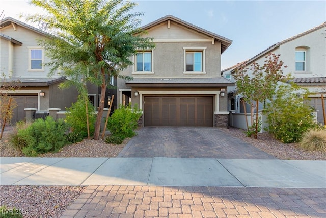 view of front facade featuring decorative driveway, an attached garage, and stucco siding