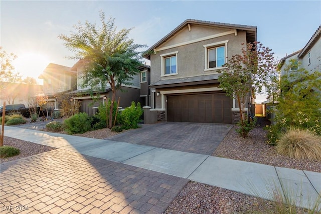 view of front of house featuring stone siding, decorative driveway, an attached garage, and stucco siding