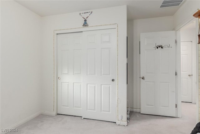 interior space featuring baseboards, a closet, visible vents, and light colored carpet