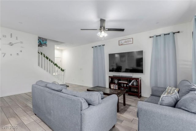 living area featuring a ceiling fan, light wood-type flooring, and stairway