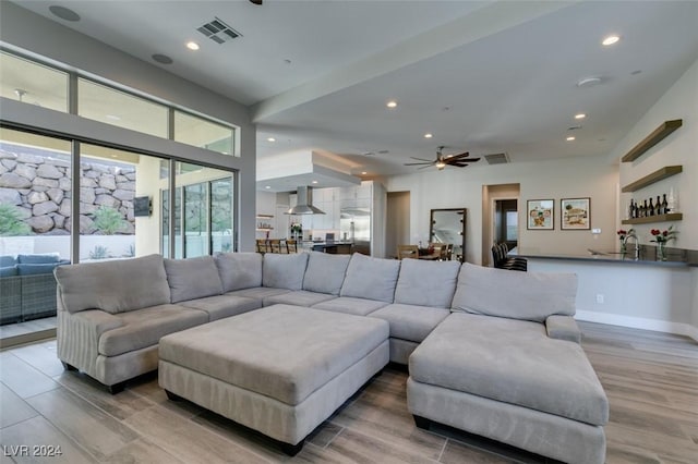 living room with ceiling fan, light hardwood / wood-style floors, and indoor bar