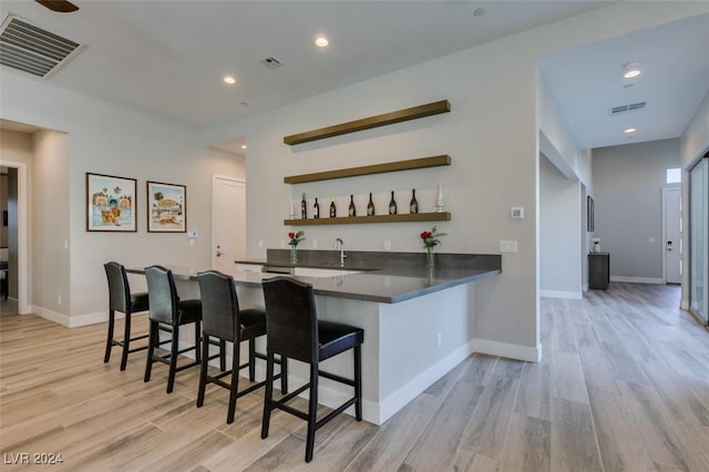 bar with light hardwood / wood-style floors and sink