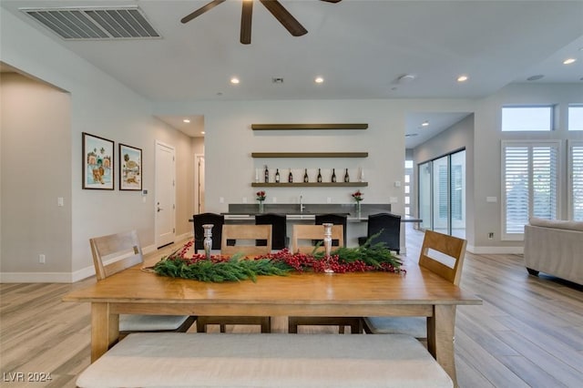 dining space featuring indoor bar, light hardwood / wood-style flooring, and ceiling fan