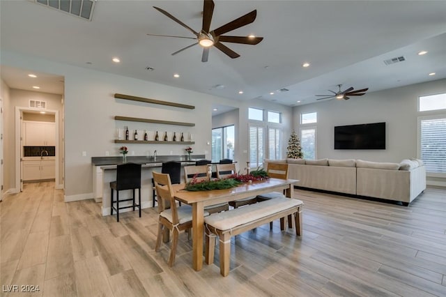 dining room featuring ceiling fan, light hardwood / wood-style flooring, and indoor bar