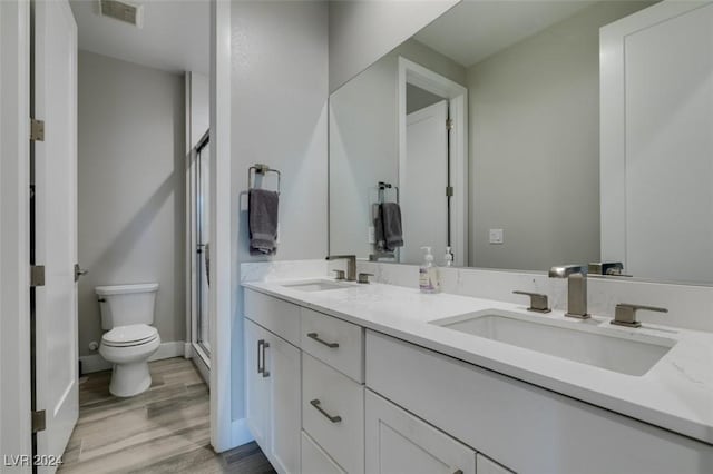 bathroom featuring hardwood / wood-style flooring, vanity, toilet, and walk in shower