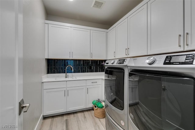 laundry area featuring cabinets, washing machine and dryer, light hardwood / wood-style flooring, and sink