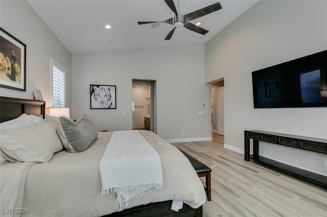 bedroom with high vaulted ceiling, ceiling fan, light hardwood / wood-style floors, and connected bathroom