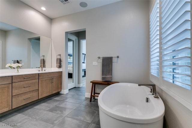 bathroom with a bathing tub, vanity, and tile patterned floors