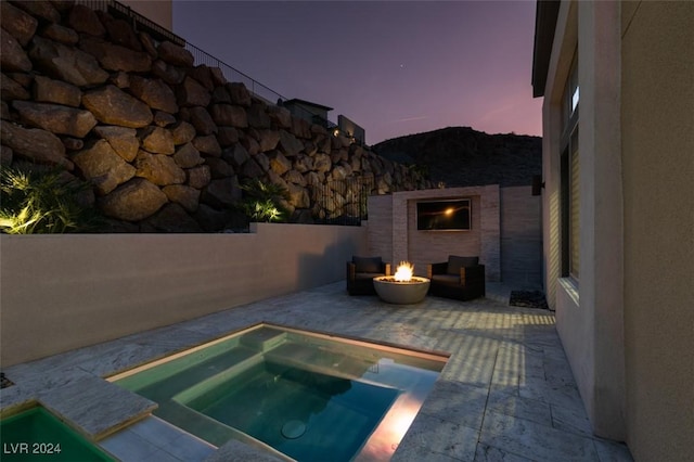 pool at dusk featuring an in ground hot tub, a patio, and a fire pit