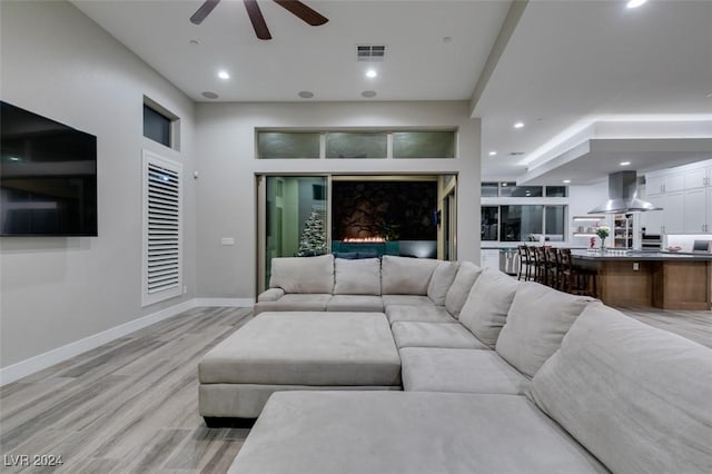 living room featuring a fireplace, light wood-type flooring, and ceiling fan