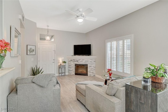 living room featuring ceiling fan, light wood-type flooring, and a tiled fireplace