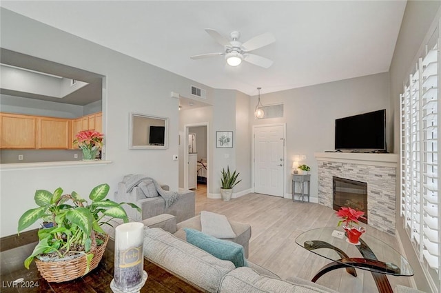 living room featuring ceiling fan, light hardwood / wood-style floors, and a fireplace