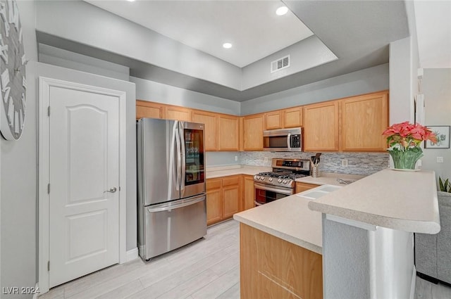 kitchen with kitchen peninsula, light hardwood / wood-style flooring, light brown cabinets, and appliances with stainless steel finishes