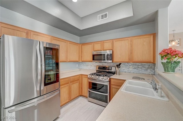 kitchen featuring sink, light brown cabinets, hanging light fixtures, light hardwood / wood-style flooring, and appliances with stainless steel finishes