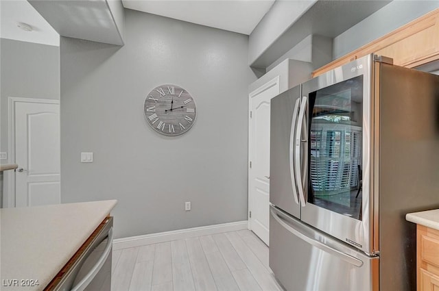 kitchen with stainless steel fridge, light brown cabinets, and light hardwood / wood-style floors