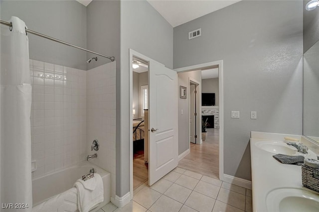 bathroom featuring shower / bath combo with shower curtain, tile patterned flooring, vanity, and a tiled fireplace