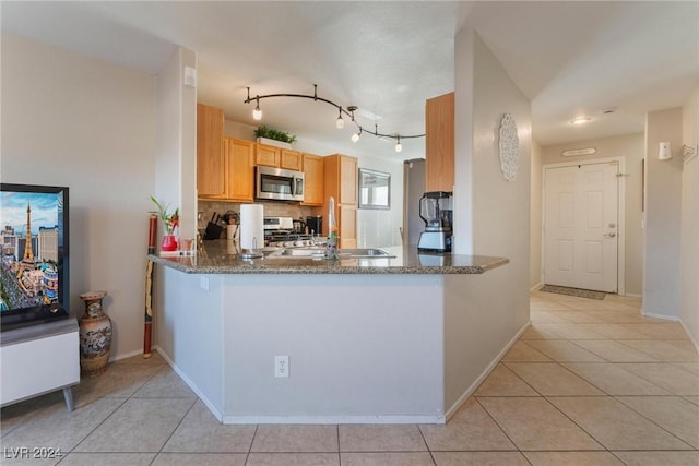 kitchen featuring appliances with stainless steel finishes, tasteful backsplash, light tile patterned floors, and sink