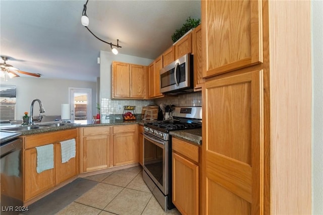 kitchen featuring appliances with stainless steel finishes, rail lighting, tasteful backsplash, sink, and light tile patterned flooring