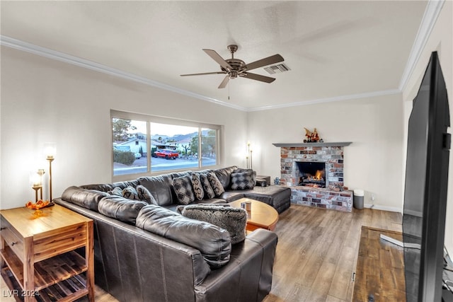 living room featuring hardwood / wood-style floors, ornamental molding, a brick fireplace, and ceiling fan