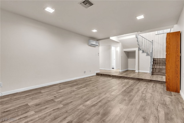 unfurnished living room featuring a wall unit AC and light hardwood / wood-style flooring